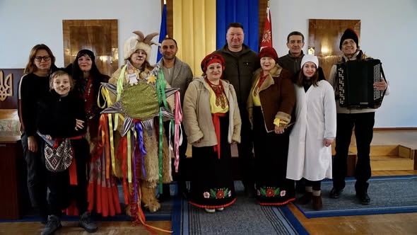 забражена група людей різного віку. частина з них одягнена в святковий одіяг, різдвяний вертеп