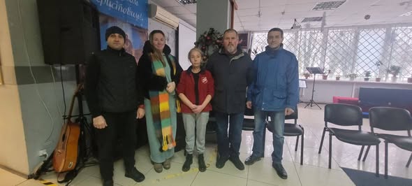 Наданий альтернативний опис до фото: група з п’яти осіб стоїть разом у приміщенні біля музичного обладнання та стільців