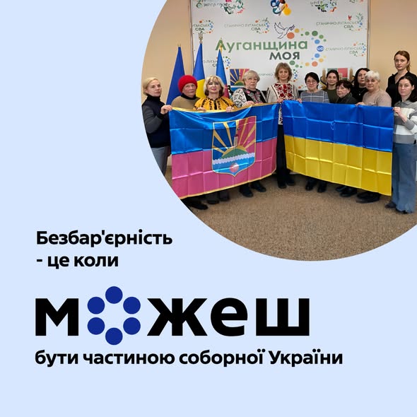Група з приблизно десяти людей, переважно жінок, стоїть у приміщенні та тримає розгорнутими два великі прапори: праворуч — синьо-жовтий державний прапор України, ліворуч — інший прапор із синьо-рожевими горизонтальними смугами та гербом. На задньому плані видно банер з написом «Луганщина моя». Великий текст на передньому плані зображення говорить: «Безбар'єрність - це коли можеш бути частиною соборної України»