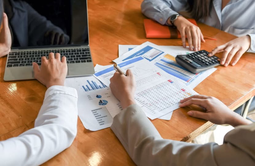 На цьому зображенні зафіксовано процес інтенсивної командної роботи, ймовірно, під час фінансового аналізу або планування проєкту.