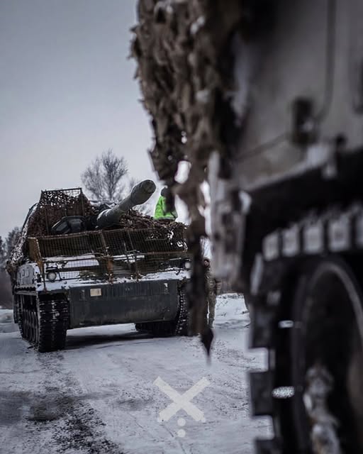 На знімку, зробленому взимку, зображено самохідну артилерійську установку PzH 2000 Збройних сил України, яка рухається засніженою дорогою, а перед нею частково видно іншу броньовану машину