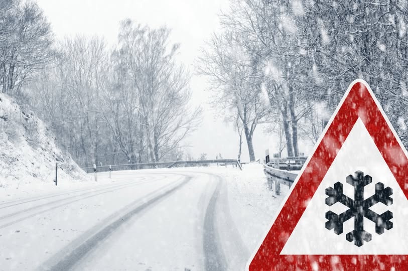 Зображення демонструє засніжену гірську дорогу взимку, на узбіччі якої розташований попереджувальний дорожній знак про ожеледицю або снігопад