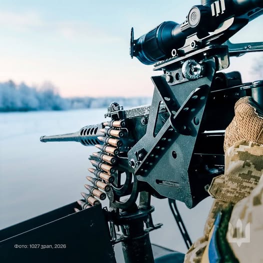 На фотографії зображено крупнокаліберний кулемет, встановлений на турелі та оснащений оптичним прицілом, який використовує військовослужбовець у польових умовах
