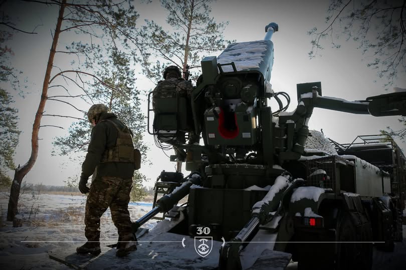 На фото зображено військовослужбовців 30-ї окремої механізованої бригади імені князя Костянтина Острозького, які працюють біля самохідної артилерійської установки в засніженому лісі