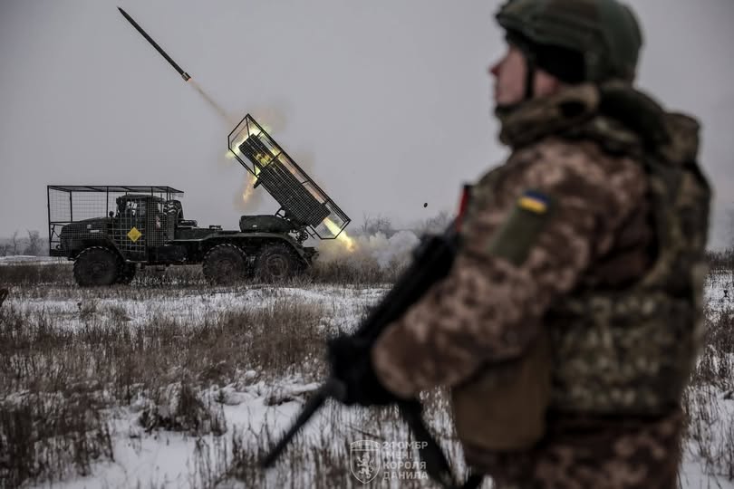 Військовослужбовець 24-ї ОМБр імені короля Данила спостерігає за залпом реактивної системи залпового вогню БМ-21 «Град» на засніженому полі. Ракета вилітає з установки, залишаючи яскравий вогняний слід