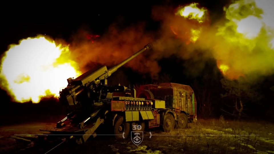 Українська самохідна артилерійська установка «Богдана» веде вогонь по ворожих позиціях у нічний час, створюючи яскраві спалахи від пострілів