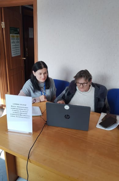 Світлина демонструє процес надання цифрових адміністративних послуг населенню, де фахівець допомагає громадянці похилого віку розібратися з електронними сервісами або оформити необхідні документи онлайн.
