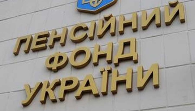 На світлині зображено фасад будівлі зі світло-кремової плитки, на якій розміщено об’ємний золотистий напис «ПЕНСІЙНИЙ ФОНД УКРАЇНИ» у три рядки, увінчаний зверху фрагментом синього гербового щита із золотим тризубом.
