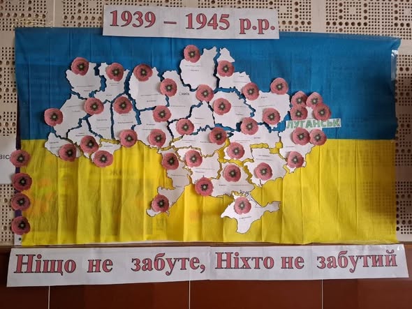На патріотичному плакаті до Дня пам’яті та перемоги над нацизмом зображено мапу України на тлі синьо-жовтого прапора, де кожна область прикрашена символічною квіткою червоного маку, а композицію доповнюють дати «1939 – 1945 р.р.» угорі, вертикальний ряд маків ліворуч та гасло «Ніщо не забуте, Ніхто не забутий» на білій стрічці внизу
