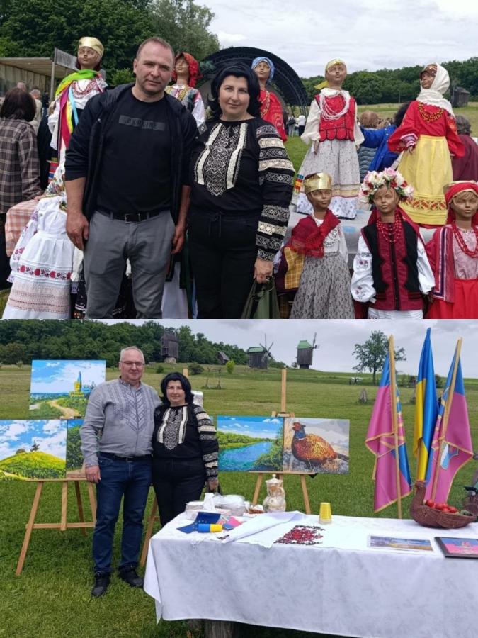 Колаж із двох фотографій показує жінку в чорній вишиванці, яка спочатку позирує поруч із чоловіком на тлі великих ляльок-мотанок, а потім з іншим чоловіком біля виставки картин, столу з прапорами та старовинних вітряків на зеленій галявині.