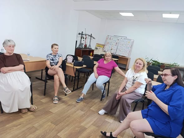 На фотографії п'ятеро жінок різного віку сидять на стільцях у колі та спілкуються в кабінеті зі світлими стінами й паркетною підлогою