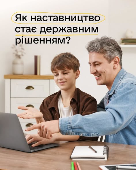 На зображенні усміхнений дорослий чоловік та хлопчик-підліток разом дивляться в ноутбук за столом, а зверху розміщено текст: «Як наставництво стає державним рішенням?».