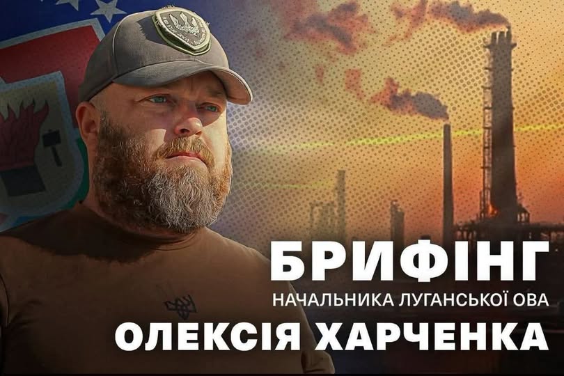 На інформаційному колажі з великим білим написом «БРИФІНГ НАЧАЛЬНИКА ЛУГАНСЬКОЇ ОВА ОЛЕКСІЯ ХАРЧЕНКА» ліворуч зображено портрет бородатого чоловіка в кепці з тризубом, а праворуч на задньому плані видно силует промислового підприємства з трубами, що димлять, у променях прийдешнього або залітного сонця.