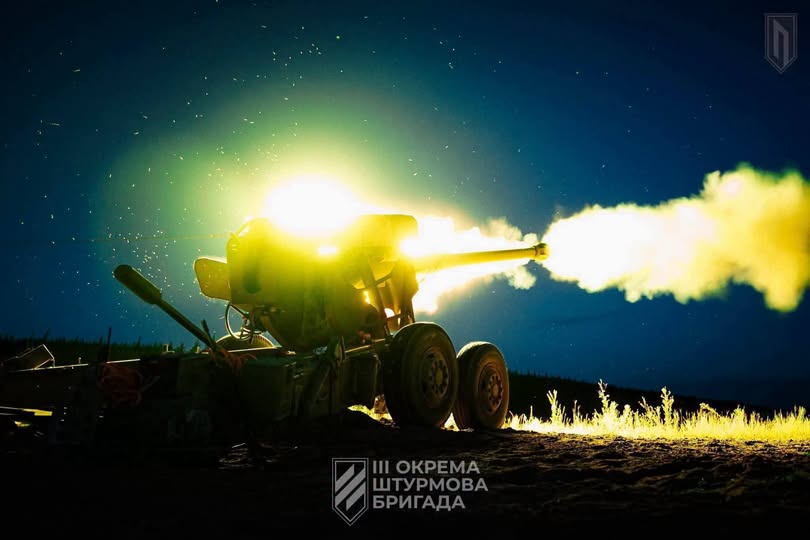 На зображенні показано артилерійську установку Третьої окремої штурмової бригади, яка здійснює потужний постріл у нічний час, утворюючи яскравий спалах світла та велику хмару диму з дула