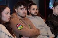 На фотографії середнім планом зафіксовано трьох молодих людей, які сидять поруч у залі.
