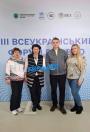 Четверо людей, дві жінки та двоє чоловіків, позують для фотографії на тлі стенду з написами «ІІІ Всеукраїнський форум» та логотипами організацій-партнерів, зокрема Міністерства розвитку громад та територій України, UNHCR, SSS