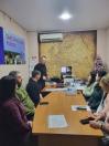 у залі засідань Щастинської районної адміністрації, про що свідчить плакат на стіні, відбувається нарада або зустріч, де присутні обговорюють робочі питання, а на столі перед ними лежить різдвяна прикраса у вигляді маленької ялинки та стоїть дата "2020" на календарі.