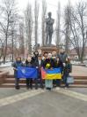 Чоловіки та жінки на фотографії стоять перед пам'ятником Володимиру Винниченку в Кропивницькому. Це перший пам'ятник видатному українському письменнику, художнику та політичному діячеві, урочисто відкритий у місті (тоді ще Кіровограді) у 2010 році