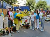 Група жінок, серед яких є учасниці патріотичного забігу, зібралася біля меморіальних банерів 30-ї окремої механізованої бригади імені князя Костянтина Острозького, щоб вшанувати пам'ять загиблих захисників України, поклавши квіти до їхніх портретів