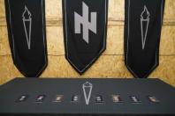 Нагородний стіл із військовими відзнаками на фоні прапорів із символікою «Ідея Nації» та стилізованими смолоскипами.