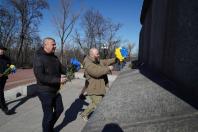 Чоловіки покладають синьо-жовті квіти до підніжжя гранітного монумента Тарасу Шевченку в межах урочистостей до дня його народження