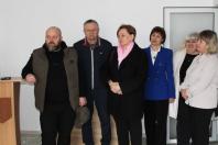Група з шести осіб (три чоловіки та три жінки) стоїть у світлому офісному приміщенні. Учасники зустрічі дивляться в один бік, за межі кадру, ніби слухають доповідача або позують для спільного фото.