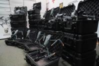 Численні сірі квадрокоптери розміщені у відкритих і закритих чорних захисних кейсах, що вишикувані рядами та високими стопками в складському приміщенні на фоні стіни з емблемою Сухопутних військ ЗСУ та логотипом «Генерал Черешня».