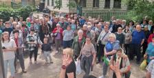 Великий натовп людей переважно старшого віку зібрався на подвір'ї біля багатоквартирного будинку на загальні збори або зустріч.