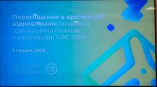 На фотографії зображено презентаційний слайд на синьо-зеленому фоні з текстом «Переміщення в архітектурі відновлення: оновлена адвокаційна позиція напередодні URC 2026», датою «5 червня, 2026» та логотипами організаторів у лівому нижньому кутку.