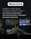На інформаційному постері з темно-сірим тлом розміщено плашку з написом «Mission Control» та текст про переваги цифрової системи фіксації бійців, під якими показано двох українських військових у камуфляжній формі зі спини, які працюють за комп'ютерами перед великими настінними моніторами з картами місцевості та відеотрансляціями.