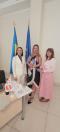 Три жінки стоять у повний зріст біля робочого столу з символікою UNFPA на тлі прапорів України та Європейського Союзу.
