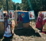 На сонячній галявині просто неба облаштовано етнографічну виставку, де на тлі тюків сіна, прикрашених синім прапором Луганської області та плакатами з описами народних строїв, вишикувані манекени у традиційному українському жіночому вбранні, хустках та автентичному намисті.