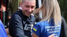 Світловолоса жінка у синій футболці з написом «Координаційний штаб з питань полонених» обіймає усміхненого коротко підстриженого чоловіка у темному світшоті з логотипом UFC.