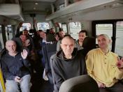 На світлині всередині салону мікроавтобуса зображена група з десяти виснажених, але усміхнених українських військовослужбовців, які махають руками та показують жест перемоги, радіючи поверненню з полону