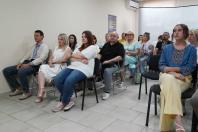 У світлій аудиторії на стільцях сидить група людей, частина з яких вдягнена у вишиванки, і всі вони зосереджено дивляться в один бік перед собою, наче слухають доповідача або переглядають відео на екрані.