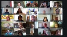 Скриншот онлайн-наради в Google Meet, що відображає сітку з понад двадцятьма віконцями учасників відеоконференції, серед яких більшість — це індивідуальні портрети колег, а також два окремі кадри зі службових кабінетів із державною символікою та прапорами України.