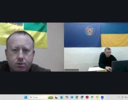 зображені начальник Широківської сільської військової адміністрації та селищний голова Машівської селищної громади, які сидять за столом та ведуть бесіду, щодо підписання Меморандуму про співпрацю. На задній стіні зображені прапори України
