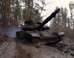 На фотографії зображено український танк Т-64БВ зразка 2022 року, який належить 67-й окремій механізованій бригаді Збройних Сил України, що рухається по багнистій лісовій дорозі