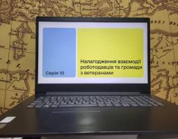 на чорному ноутбуці Lenovo, розташованому на старовинній карті, на екрані відображається презентаційний слайд українською мовою з написом «Серія 10» та темою «Налагодження взаємодії роботодавців та громади з ветеранами».