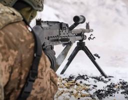 на засніженому полігоні український солдат у військовій формі веде вогонь із великокаліберного кулемета, про що свідчить розкидана на снігу стріляна гільза та напис «210 ШТУРМОВИЙ» на фото.