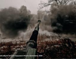 Фотографія зблизька артилерійської гармати 26-ї окремої артилерійської бригади імені генерал-хорунжого Романа Дашкевича під час пострілу, що здіймає велику хмару диму на засніженому полі.
