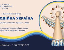 На зображенні — рекламний банер Національного конкурсу «Благодійна Україна» за 2025 рік, організованого Асоціацією благодійників України. На банері домінує синьо-жовта кольорова гама. У центрі розташовано великий напис «БЛАГОДІЙНА УКРАЇНА» та менший текст «Благодійність на захисті України» - 2025. Праворуч зображено стилізовану дерев'яну фігурку ангела з розписаними крилами та німбом. У нижній частині вказані веб-сайт blagoukraine.org та номер телефону, а також QR-код