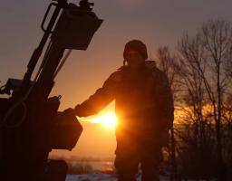 Український захисник у променях вечірнього сонця біля зенітної установки під час чергування