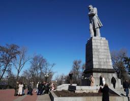 Група людей зібралася біля підніжжя високого пам’ятника Тарасу Шевченку на Монастирському острові в Дніпрі сонячного весняного дня.