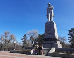 Група людей позирує для спільного фото біля підніжжя величного пам'ятника Тарасу Шевченку на Монастирському острові в Дніпрі за ясної сонячної погоди.