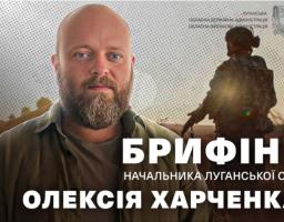 На інформаційному банері Луганської обласної державної адміністрації зображений портрет світлоокого бородатого чоловіка, Олексія Харченка, на фоні силуету військового у спорядженні та великого білого напису «БРИФІНГ НАЧАЛЬНИКА ЛУГАНСЬКОЇ ОВА», що анонсує офіційний виступ керівника області.