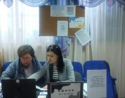 У світлій кімнаті з синіми кріслами дві жінки сидять за робочим столом перед ноутбуками біля таблички з написом «Єдине вікно», а позаду них на стіні висить дошка оголошень із гербом Луганської області.