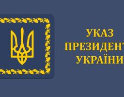 На синьому фоні зображено емблему з тризубом у квадратній рамці з виноградної лози та жовтий напис "УКАЗ ПРЕЗИДЕНТА УКРАЇНИ" праворуч від неї