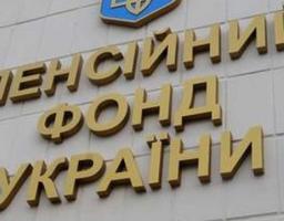 На світлині зображено фасад будівлі зі світло-кремової плитки, на якій розміщено об’ємний золотистий напис «ПЕНСІЙНИЙ ФОНД УКРАЇНИ» у три рядки, увінчаний зверху фрагментом синього гербового щита із золотим тризубом.