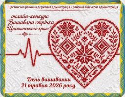 Святковий банер Щастинської районної державної та військової адміністрації у рамці кольорів українського прапора містить червоні написи про онлайн-конкурс «Вишивана стрічка Щастинського краю» до Дня вишиванки 21 травня 2026 року, розміщені на білому текстурованому тлі ліворуч від великого серця, що вишите червоними нитками традиційним орнаментом і з'єднане з лінією пульсу